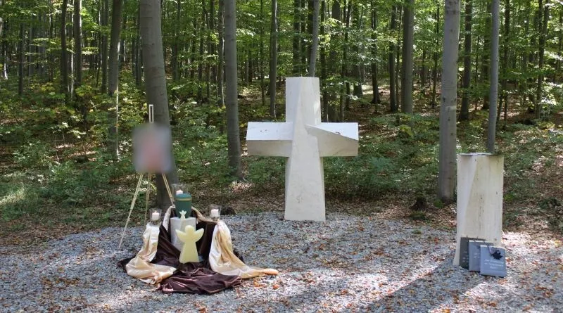 Eine liebevoll gestaltete Waldgrabstätte mit Kreuz, Urne, Kerzen und natürlicher Umgebung.